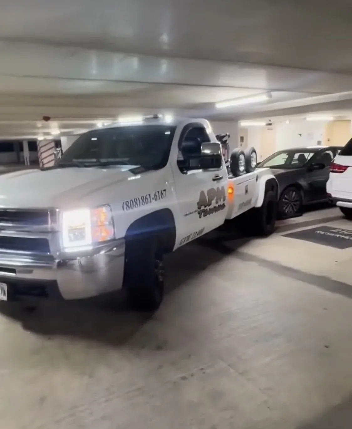 APM Towing recovery truck working inside a restricted-height parking garage