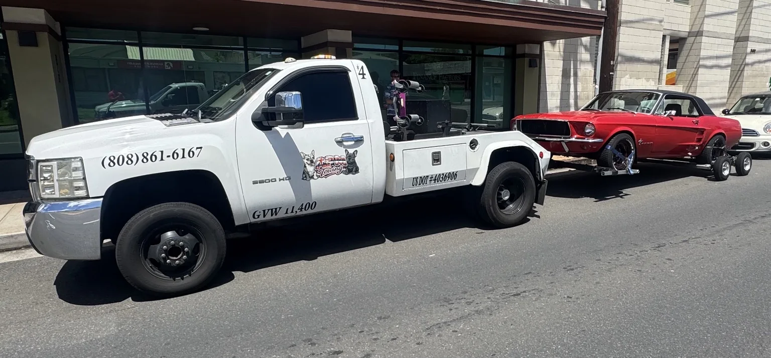 APM Towing wheel-lift truck transporting a red Mustang